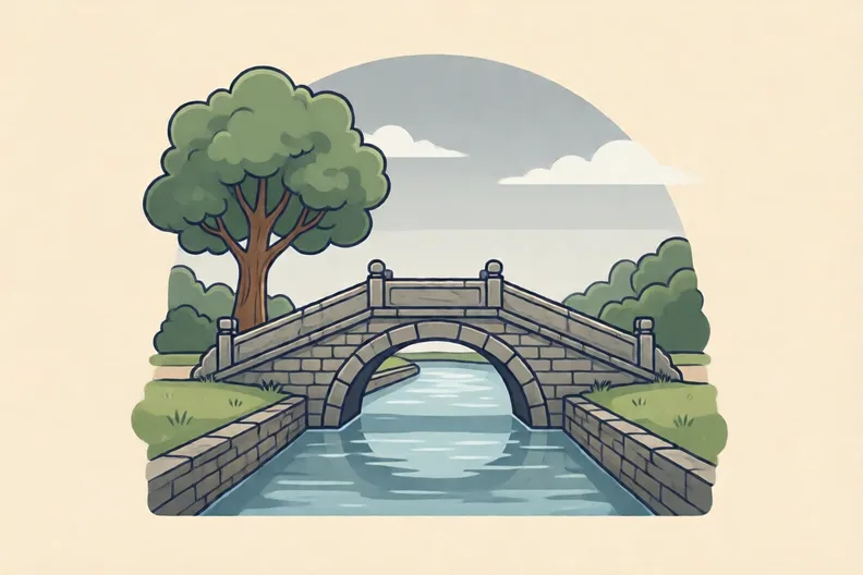 A stone footbridge over a calm canal with a tree on the bank