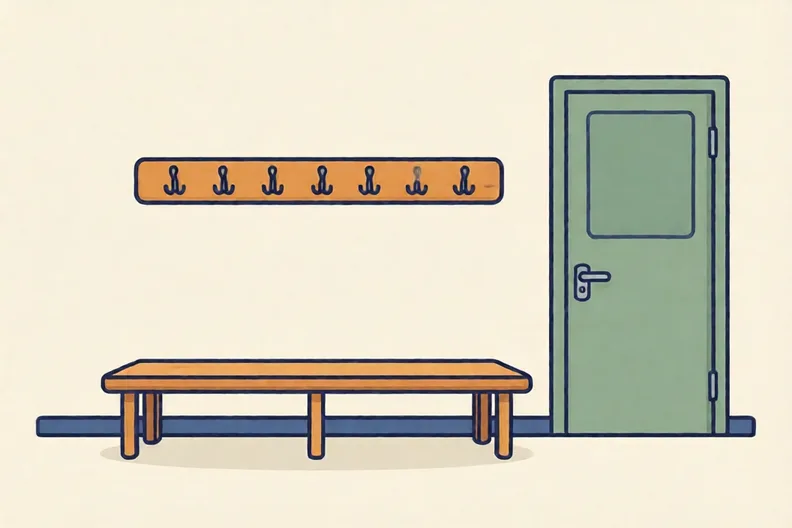 A school cloakroom with a row of empty coat hooks above a bench