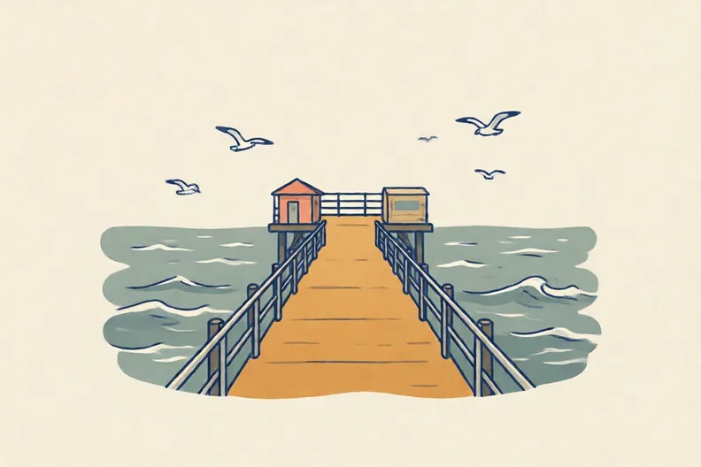 A seaside pier on a windy day with grey waves and gulls over the sea