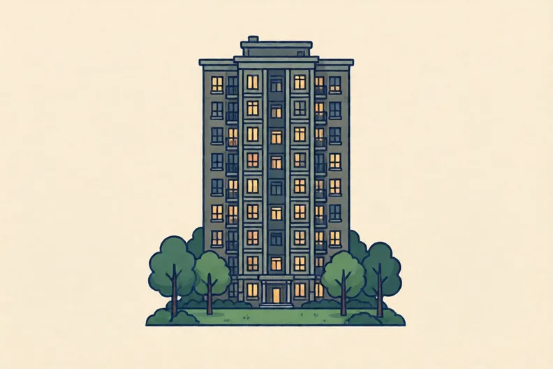 A tall tower block at dusk with lit windows and a small park below