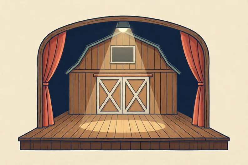 An empty theatre stage with a painted barn backdrop and one spotlight