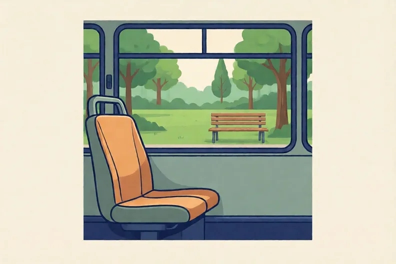An empty bus seat by a window looking out at a green park with a bench