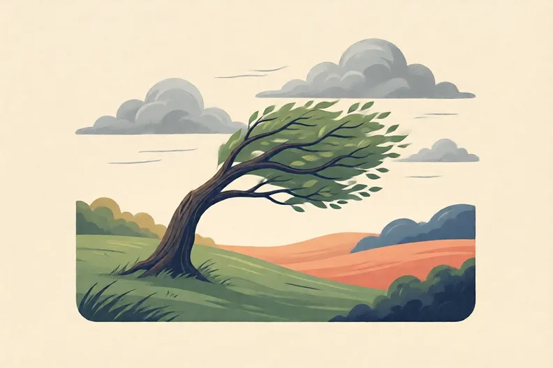 A windy hillside with one bent tree under racing clouds