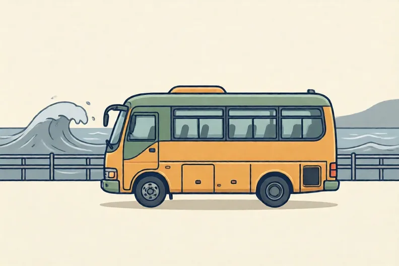 A coach parked by a seaside promenade on a windy day