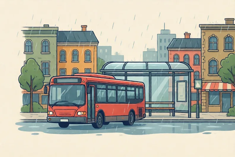 A red bus at a wet bus stop in a town street