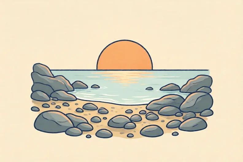 A pebbly beach at sunset with grey stones and a pale sea
