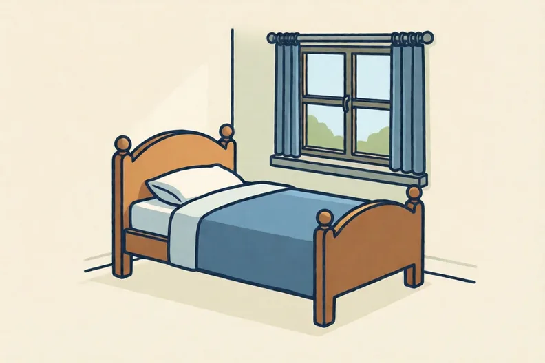 A single bed with a blue cover, neatly made, in a small bedroom