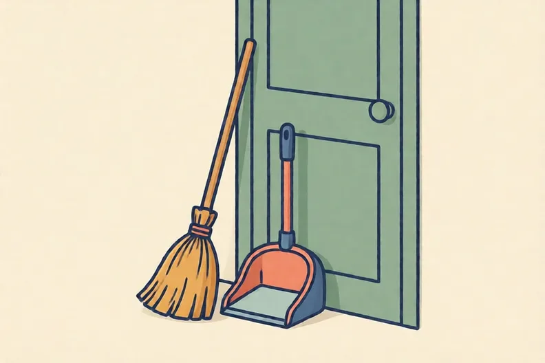 A broom and a dustpan leaning against a wall by a back door