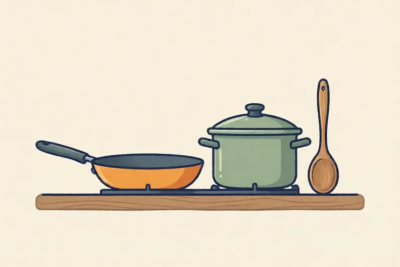 A kitchen counter with a frying pan, a saucepan and a wooden spoon