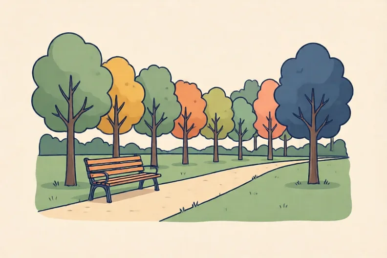 A quiet park with a bench beside a path and a row of trees