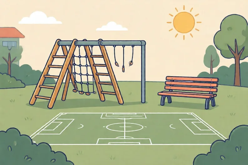 An empty school playground with a climbing frame and a football on the grass